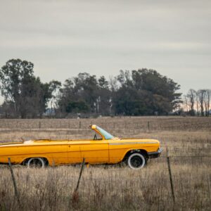 Vintage yellow convertible in a serene rural field in Coronel Pringles, Argentina, evoking nostalgia in an open landscape.